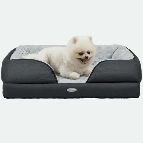 White fluffy small dog lying in a charcoal bolster dog bed with a grey plush inner