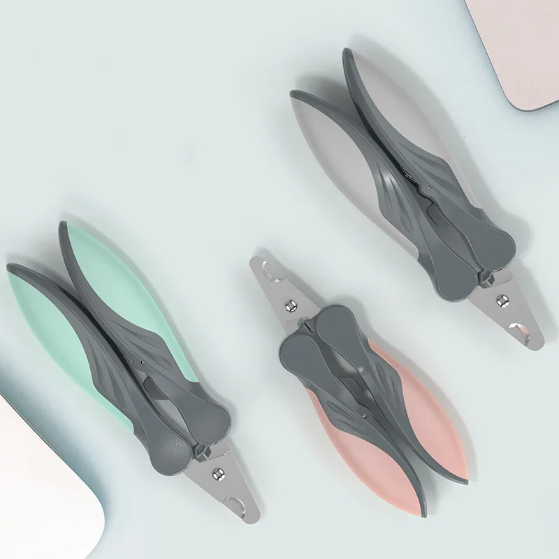 Three pairs of nail clippers in green, grey and pink on a pale blue surface