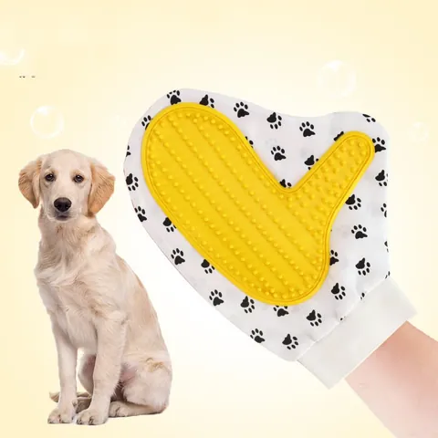 Hand wearing the grooming glove with its yellow silicone nub pad, next to a sitting pale golden dog